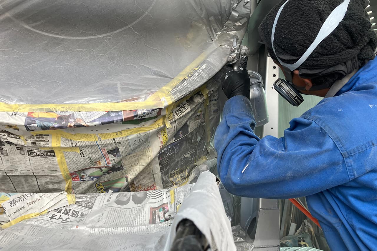 車両の隙間や細部の塗装・補修作業を丁寧に行う作業員